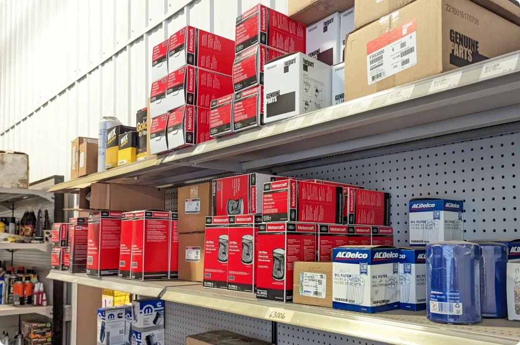 1023 Diesel & Fleet: Shelves filled with various automotive parts, including red and white Monroe boxes and blue and white ACDelco boxes, inside a store. Some shelves also hold brown boxes labeled Genuine Parts.