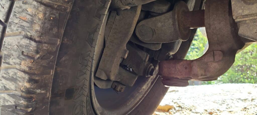Image of a close-up truck wheel assembly showing worn suspension components and undercarriage parts.