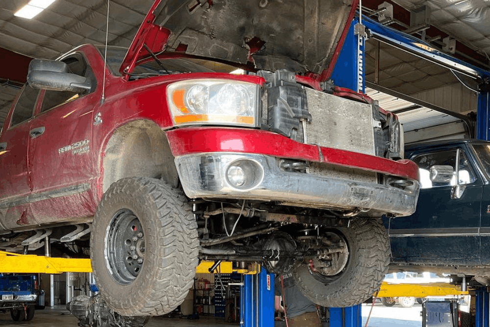 Front axle replacement and suspension repair in Palmer, AK at 1023 Diesel & Fleet. Image of a lifted Ram truck with the hood open and front suspension components exposed for service.