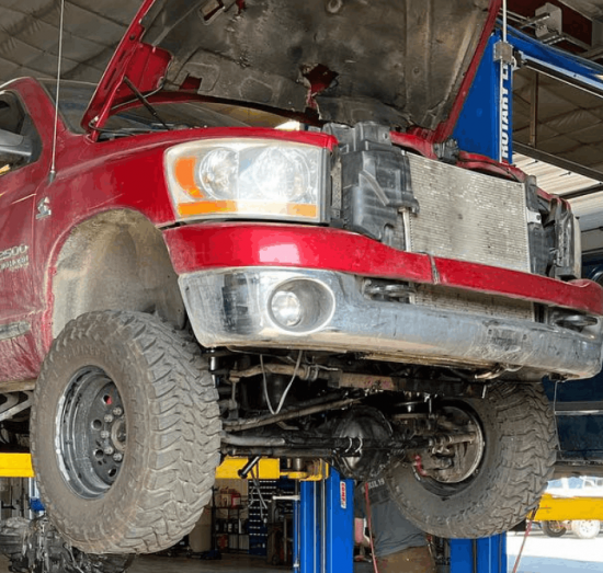 Front axle replacement and suspension repair in Palmer, AK at 1023 Diesel & Fleet. Image of a lifted Ram truck with the hood open and front suspension components exposed for service.