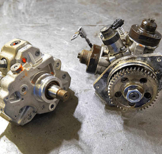 CP3 conversion, diesel repair in Palmer, AK at 1023 Diesel & Fleet. Side-by-side comparison of a new CP3 fuel pump and an older pump on a workbench, highlighting components used in Duramax CP3 conversion.